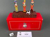 two figurines in a red box on a table with a card