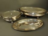 three silverplated serving dishes on stands on a table