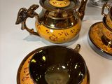 three teapots and two cups on a table