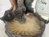 a figurine of a woman sitting on top of a fish