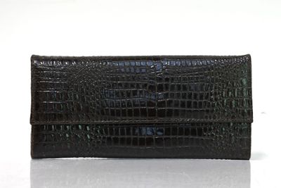 une photo d'un sac à main en peau d'alligator noir posé sur une surface blanche