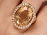 an image of a woman ' s hand holding a ring with a large yellow stone