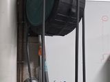 a whiteboard on the wall in a garage with a hose attached to it