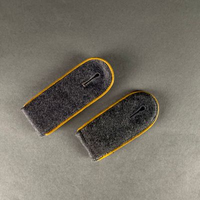 pair of grey and yellow felt ear plugs on a gray surface