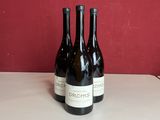 trois bouteilles de vin sont posées sur un comptoir devant un mur rouge