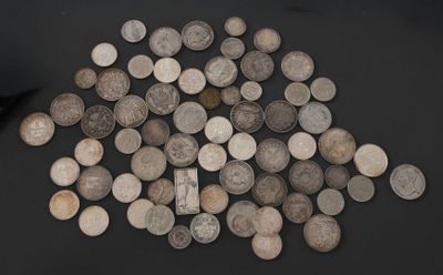 a pile of old silver coins on a black surface
