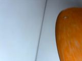 an orange toilet seat sitting in a bathroom next to a white wall
