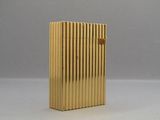 a gold lighter sitting on a table with a gray background