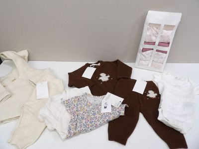 a pile of baby clothes on a table next to a bag of diapers