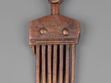 a wooden comb with a face on it on a gray surface