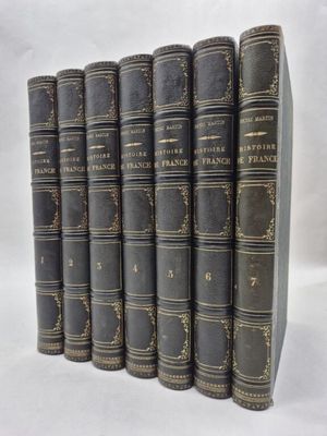 six old books are lined up in a row on a white surface