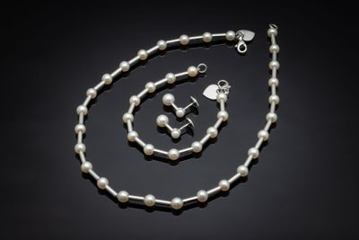 un gros plan d'un collier et d'un bracelet ornés de perles sur fond noir