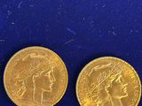 two gold coins on a blue surface, one of which has a woman ' s head and one of which is a man ' s head