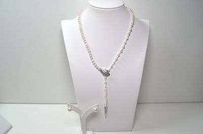 un collier et des boucles d'oreilles posés sur un mannequin, sur une surface blanche