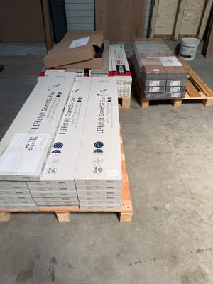 Plusieurs piles de cartons sont empilées sur des palettes dans un entrepôt
