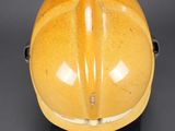 yellow hard hat sitting on a black base on a gray surface