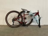 un vélo appuyé contre un mur, sur lequel est posé un sac en plastique