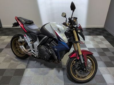 une moto rouge, blanche et bleue garée sur un sol à damier