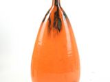 an orange vase with a black stripe on the bottom