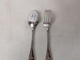 two forks and a spoon are sitting on a white surface
