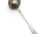 une cuillère en argent avec un manche de cuillère sur une surface blanche