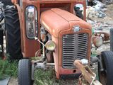 an old rusted orange truck parked in a junkyard