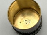 a gold cup with a black lid sitting on a table