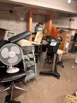 a fan sitting on a chair in a cluttered room