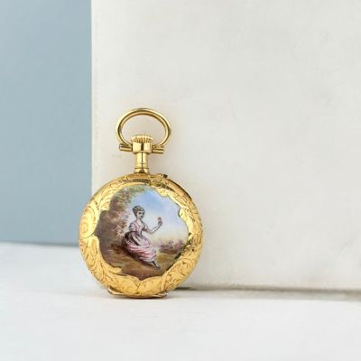 une image représentant une montre de poche en or sur laquelle figure le portrait d'une femme