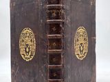 an old book with a gold - plated cover sitting on top of a white surface