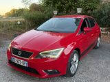 La voiture rouge est garée devant un bâtiment en pierre.