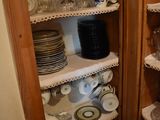 many plates and cups on the shelves in the kitchen