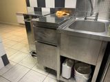 un évier en acier inoxydable dans une cuisine aux murs à carreaux noirs et blancs