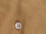 the button on a brown shirt has a small hole in it