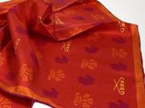 a close up of a red and orange scarf on a white surface