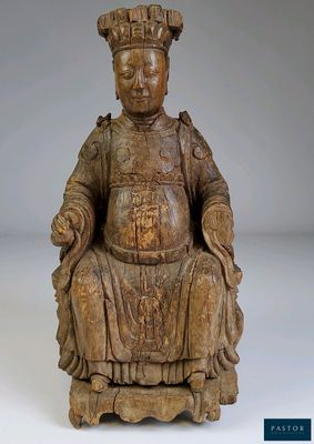 une statue en bois représentant un homme assis sur une chaise