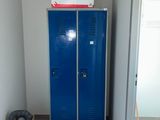un casier bleu dans une pièce où s'entassent des cartons, les uns sur les autres, par terre