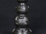 a close up of a black vase with three faces on it