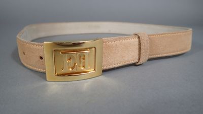 ceinture en cuir beige avec une boucle dorée sur un fond gris