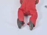a small red doll laying on the floor next to a pair of scissors