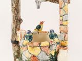 a ceramic water fountain with birds perched on a branch