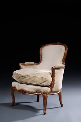 une photo représentant une chaise et un pouf dans une pièce sombre