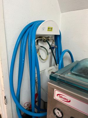 un tuyau bleu fixé au mur, à côté d'un réservoir d'eau