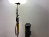 a lamp that is on a tripod next to a trash can