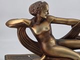 bronze statue of a woman sitting on a book with a book in her lap