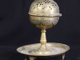 an antique brass plate with a lid and stand on a black background
