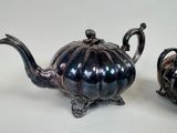 two silver teapots sitting next to each other on a table