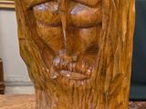 une sculpture en bois représentant un homme barbu, posée sur une table