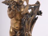 statue of cupid playing the flute on a branch of a tree