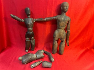 Deux figurines en bois sont placées l'une à côté de l'autre sur un tissu rouge.